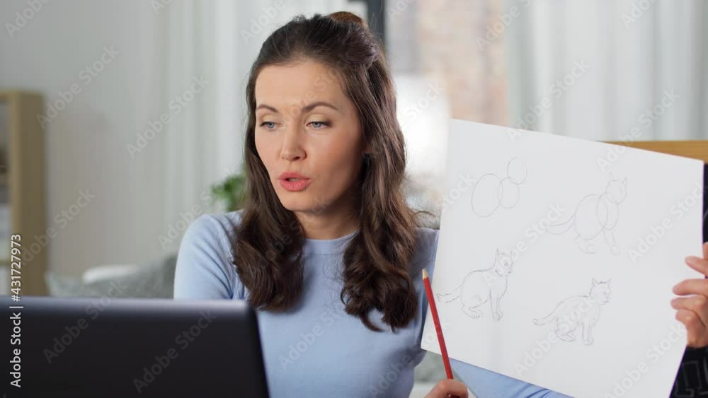 distant education, primary school and teaching concept - female teacher with laptop computer and tutorial picture of cat drawing having online class of arts at home