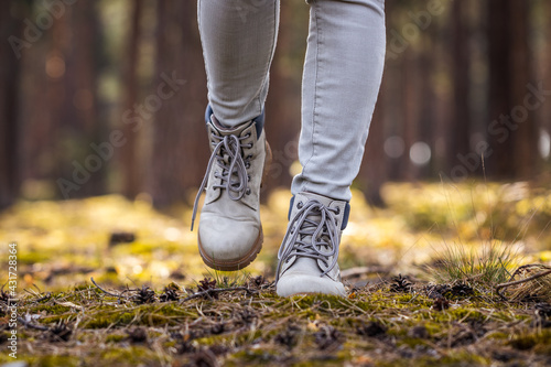 Hiking boots. Hiker walking in woodland. Female legs wearing leather sports shoes in forest