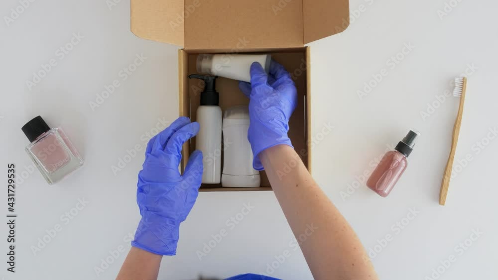 delivery, shipping and pandemic concept - hands in protective medical gloves packing parcel box with cosmetics and beauty products