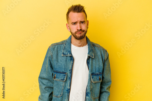 Young tattooed caucasian man isolated on yellow background sad, serious face, feeling miserable and displeased.