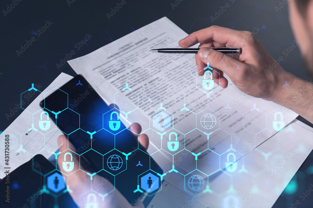 A businessman in casual wear signing the contract to prevent probability of risks in cyber security. Checking the phone. Padlock Hologram icons over the working desk. A businessman in casual wear signing the contract to prevent probability of risks in cyber security. Checking the phone. Padlock Hologram icons over the working desk.