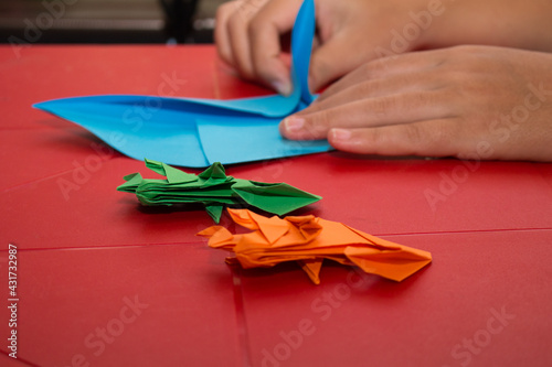 colorful origami chameleons falling on a red table