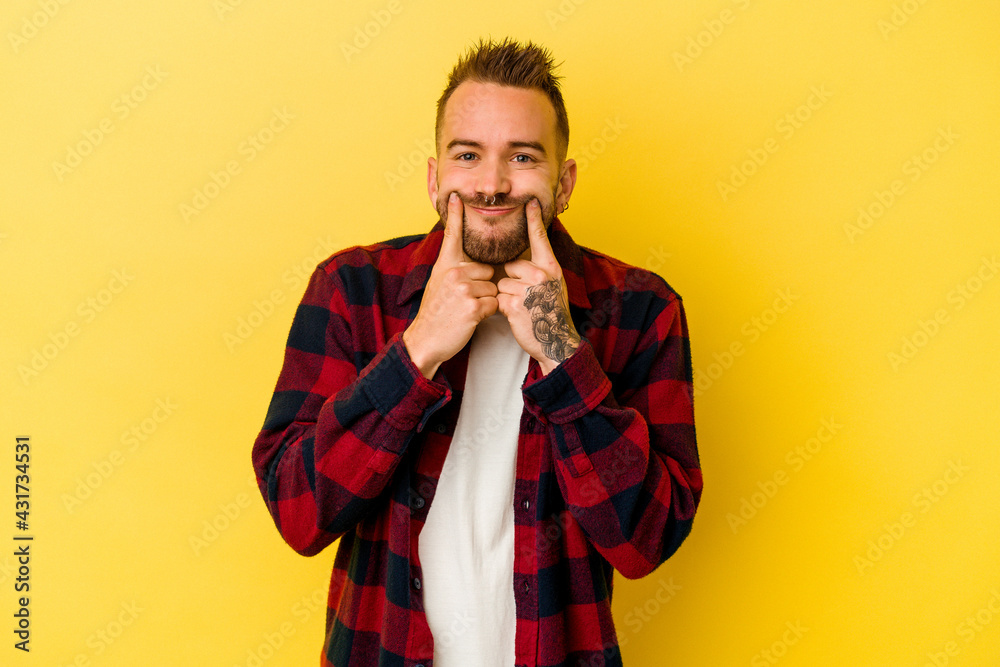 Young tattooed caucasian man isolated on yellow background doubting between two options. Young tattooed caucasian man isolated on yellow background doubting between two options.