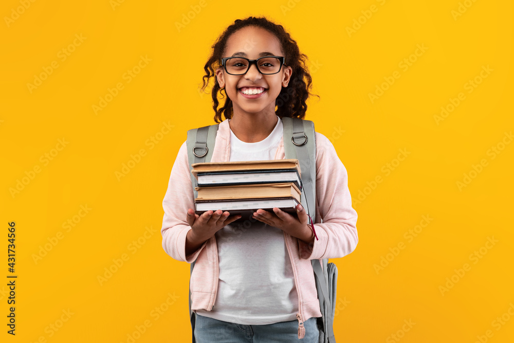 Smiling black girl holding pile of books Smiling black girl holding pile of books