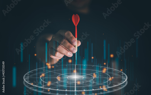 Foto Businessman throwing red arrow dart to virtual target dart board