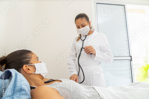 Foto Female doctor measuring pressure of patient with mask.