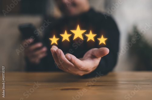 hand of customer or client holding the stars to complete five stars. with copy space. giving a five star rating. Service rating, satisfaction concept.
