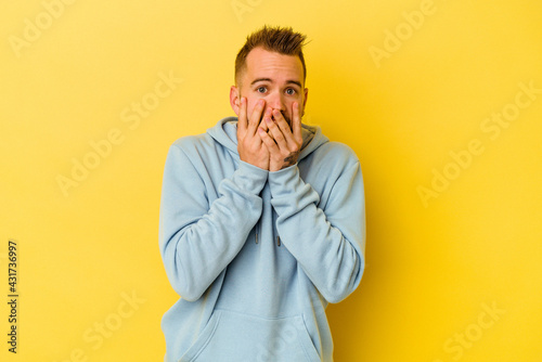 Young tattooed caucasian man isolated on yellow background shocked, covering mouth with hands, anxious to discover something new.