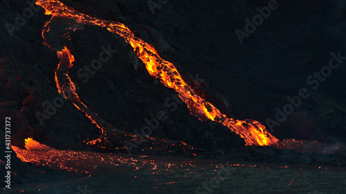 Close-up view of volcano eruption in Geldingadalir valley near Fagradalsfjall mountain, Grindavík, Reykjanes peninsula, southwest Iceland with with flowing hot and flowing lava in the dark. photo