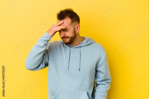 Young tattooed caucasian man isolated on yellow background touching temples and having headache.