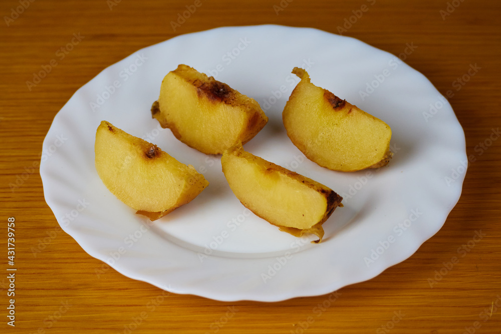 Tasty Baked Apple slices on a plate and wooden background