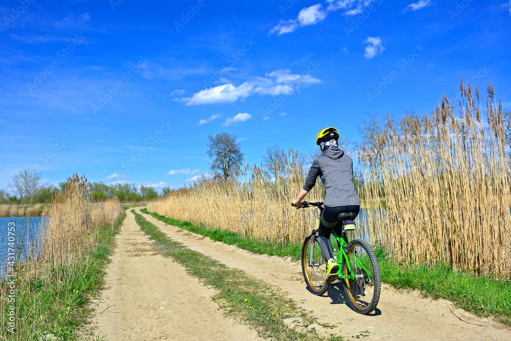Woman riding a bicycle on a sunny spring day. Outdoor recreation.
