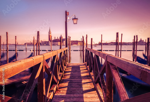 Pier with gondolas in long exposure in venice at sunset