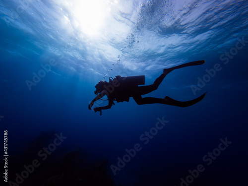 Silhouette of a diver with bubbles. Sunlight behind a diver. 