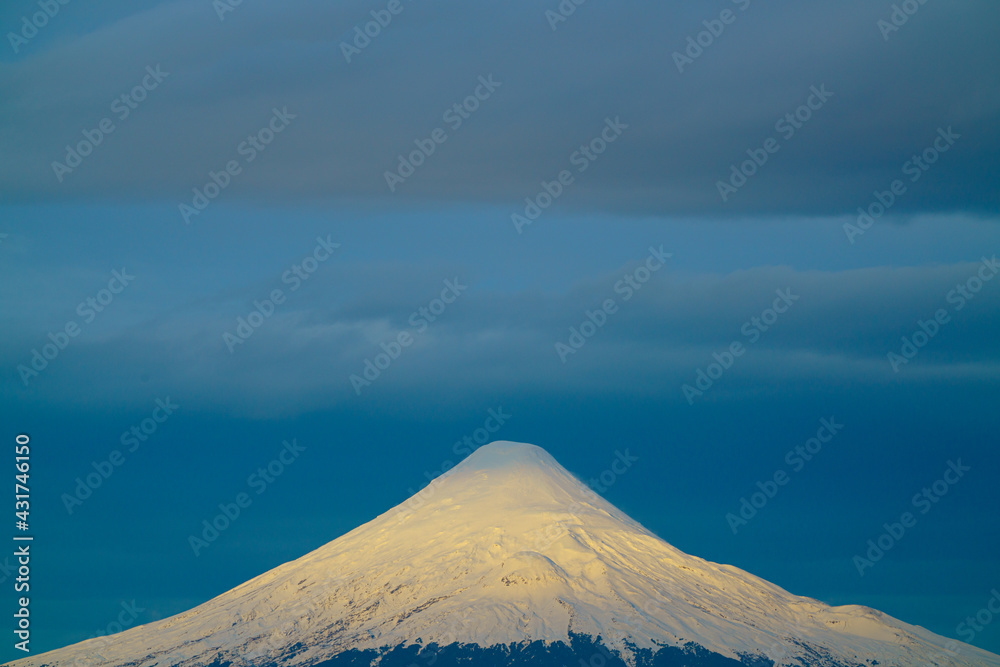 dramatic light at the beginning of sunset, illuminating the snowy summit of the Osorno volcano dramatic light at the beginning of sunset, illuminating the snowy summit of the Osorno volcano