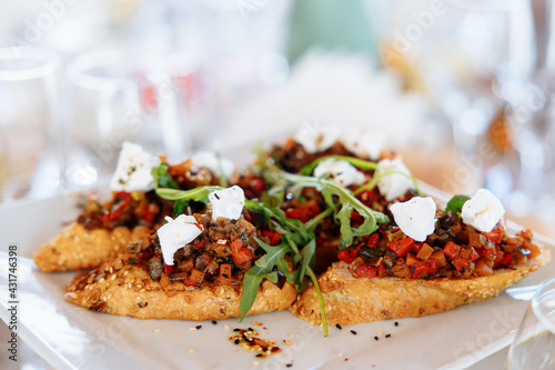 Italian appetizer on white slate background. Crusty bruschetta with concasse tomatoes, stracciatella cheese decorated with rucola. Delicious and healthy restaurant meals, copy space, closeup photo