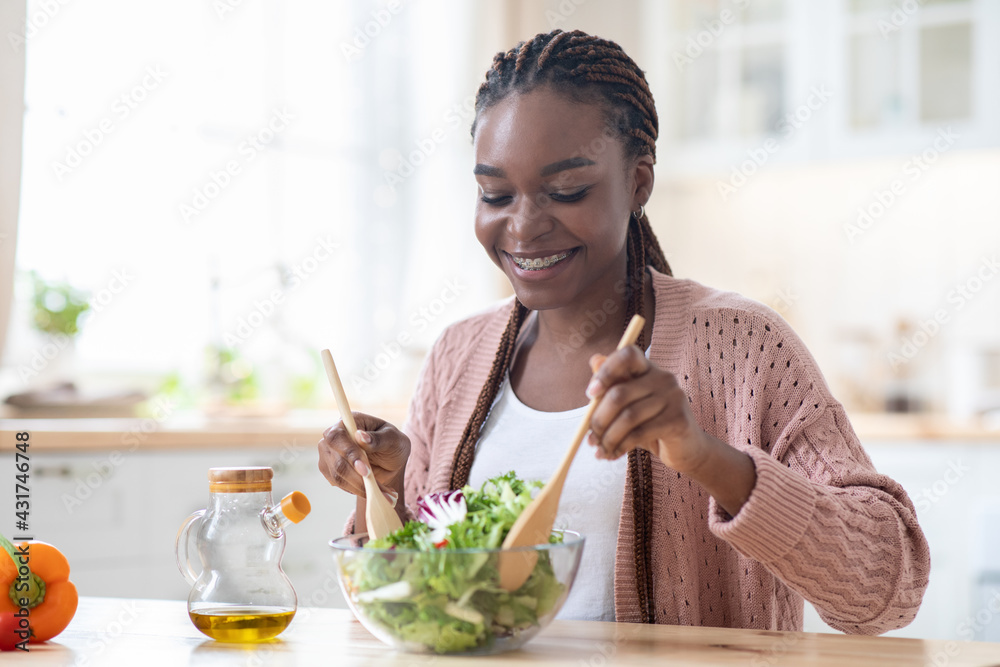 Healthy Nutrition Concept. Happy Black Female Cooking Fresh Vegetable Salad In Kitchen