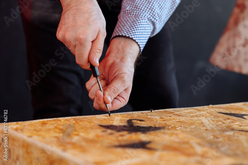 A man opens a wooden plywood box with a screwdriver. Unpacking the parcel in the crate.
