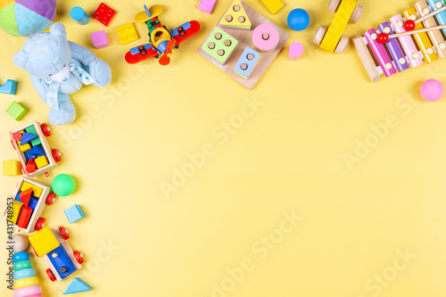 Baby kids toy frame with educational, developmental, musical, learning toys on pastel yellow background. Top view