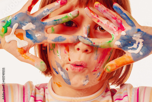 Portrait of huppy beautiful young child girl with colorful painted face and hands.