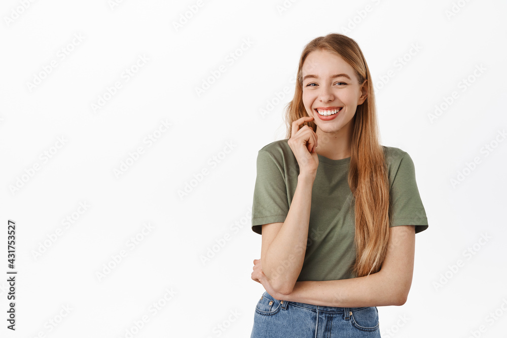 Cute caucasian girl laughing, smiling with white perfect teeth, looking joyful at camera as if having funny conversation, standing in t-shirt against white background Cute caucasian girl laughing, smiling with white perfect teeth, looking joyful at camera as if having funny conversation, standing in t-shirt against white background