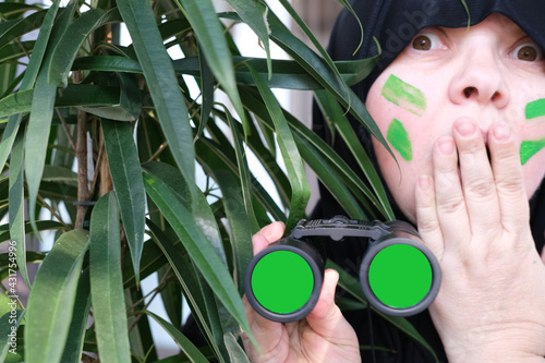 Fotografie close-up curious islamic woman in war paint, holding field binoculars with zoom,