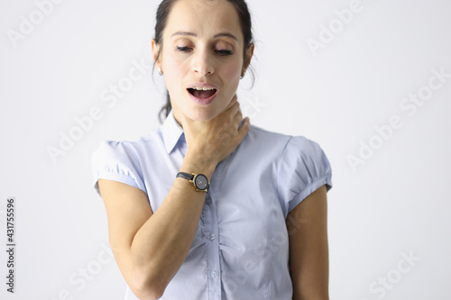 Frustrated woman holds her throat with her hand and coughs photo