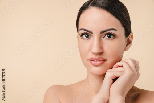 Close up portrait of woman`s face with clean skin isolated over beige background. Caucasian white young girl with bare shoulders naked relaxed for beautician. Spa, skin and body care concept