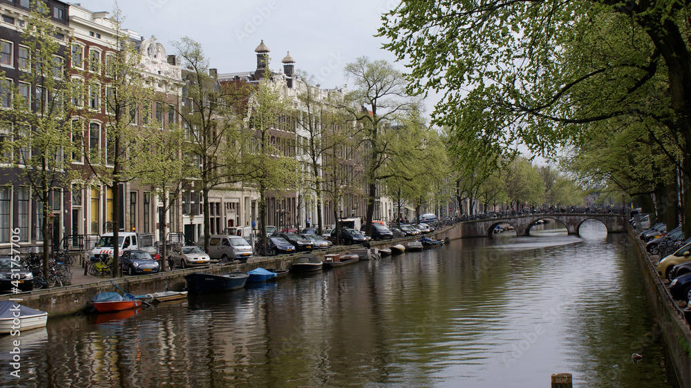 Amsterdam, Netherlands, April 2011: A cityscape of canal with reflections and boats with typical Dutch buildings in springtime.
