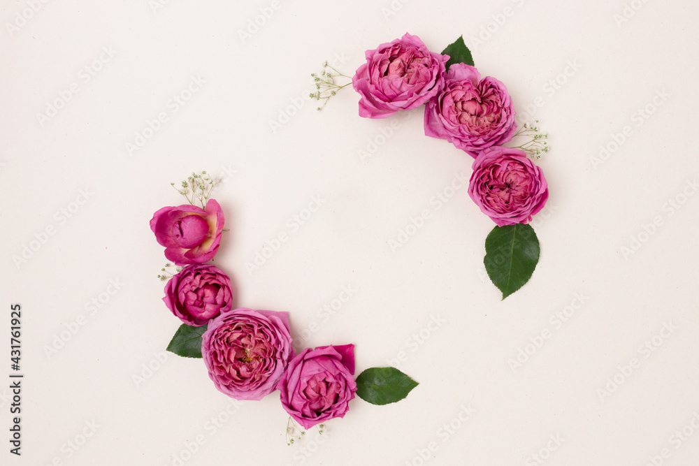 Round frame made of rose and green leaves on a beige background. Flower wreath. Festive concept. Round frame made of rose and green leaves on a beige background. Flower wreath. Festive concept.