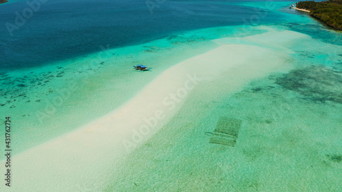 Island with a sandy beach and azure water surrounded by a coral reef and an atoll, aerial view. Mansalangan sandbar, Balabac, Palawan, Philippines. Summer and travel vacation concept