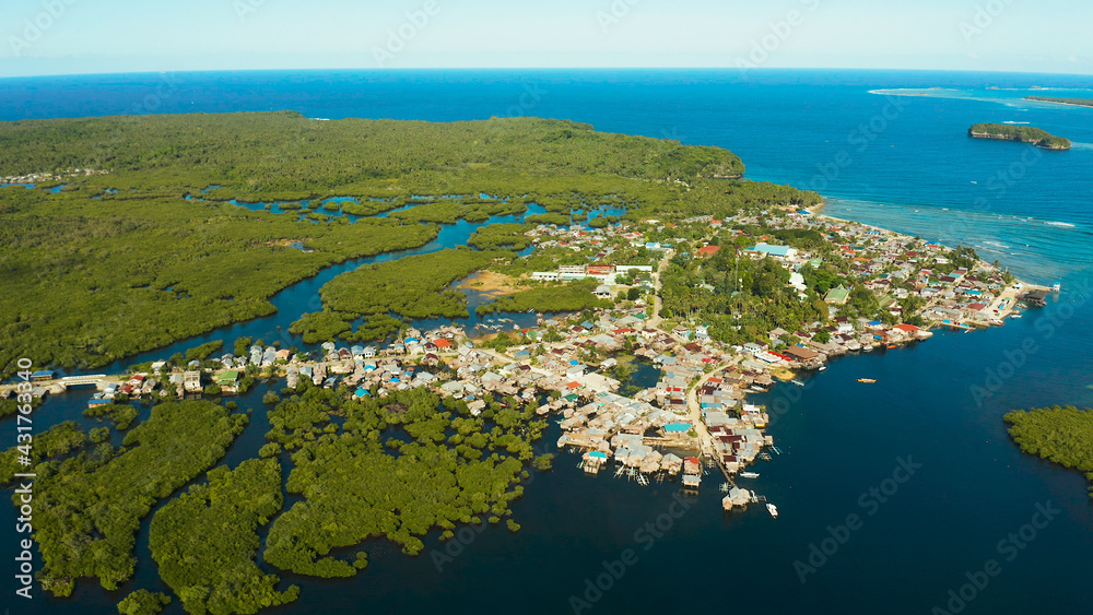 City in wetlands and mangroves on the ocean coastline aerial view. Siargao island, Philippines.