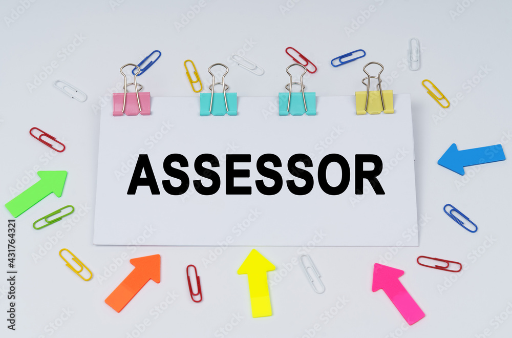 On the table there are paper clips and directional arrows, a sign that says - ASSESSOR On the table there are paper clips and directional arrows, a sign that says - ASSESSOR