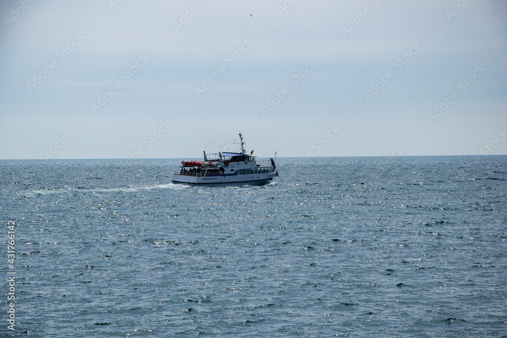 A tourist boat goes by the sea. A sailing yacht sails on the sea, a yacht is a dream.