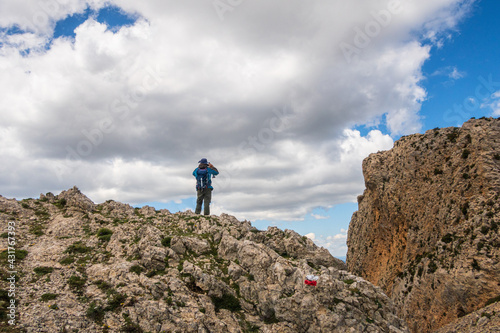 Lonely hiker, walking up a mountain, on a sunny and cloudy day, through the Alicante mountain of La Mallada del Llop.