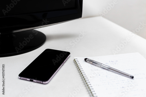 Smartphone, screen of computer pen and notebook for note on the white desk with copy space