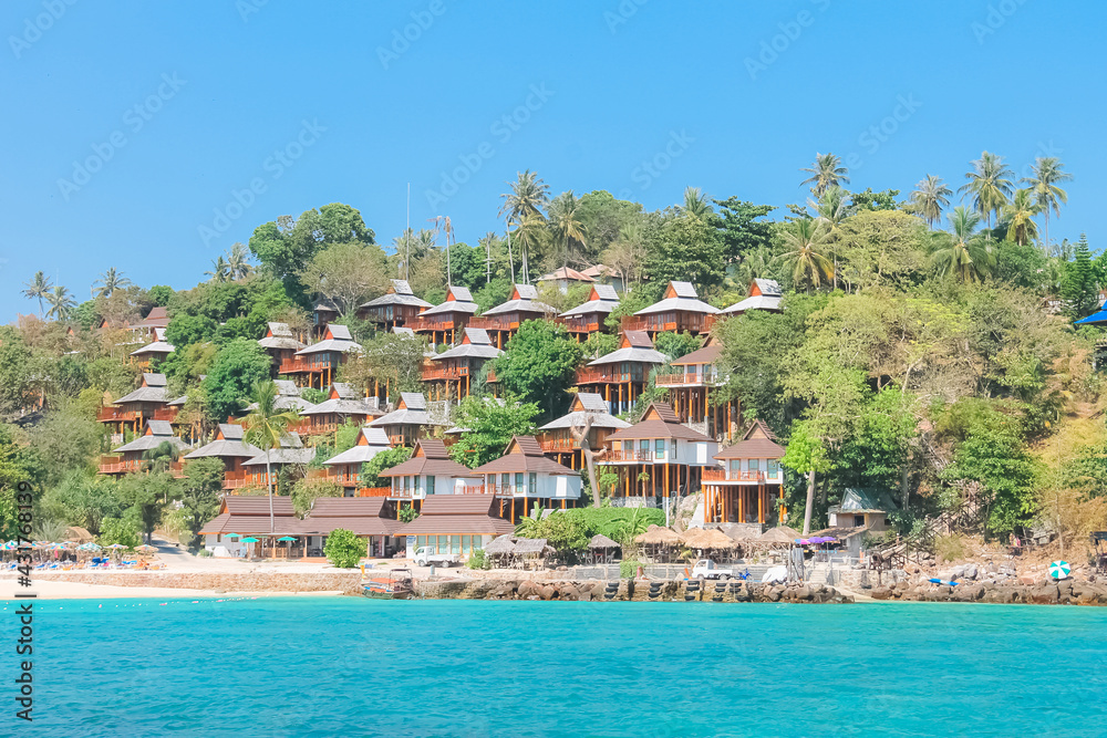 Oceanfront holiday resort bungalows in the tropical Phi Phi islands on the Andaman Sea in Thailand on a clear blue sky sunny day.