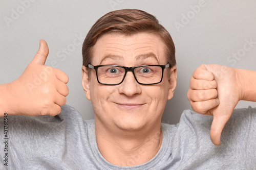 Portrait of happy man showing thumb up and thumb down gestures