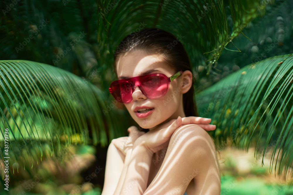 woman in sunglasses in the jungle and green leaves naked shoulders exotic woman in sunglasses in the jungle and green leaves naked shoulders exotic