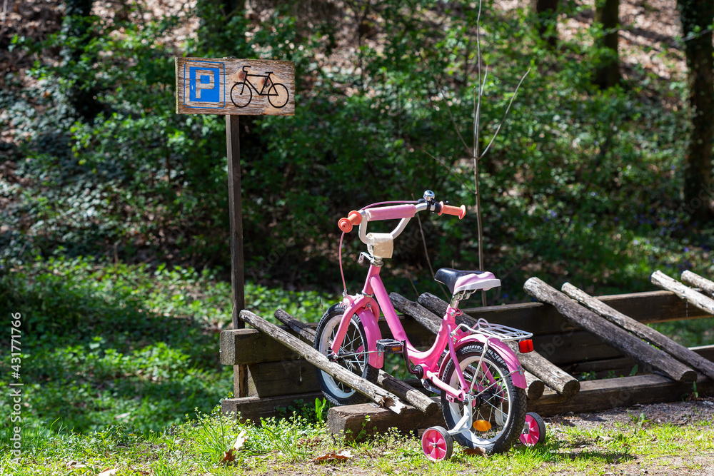 Fototapeta premium A small, pink children's bicycle is parked in a designated area with a parking sign.