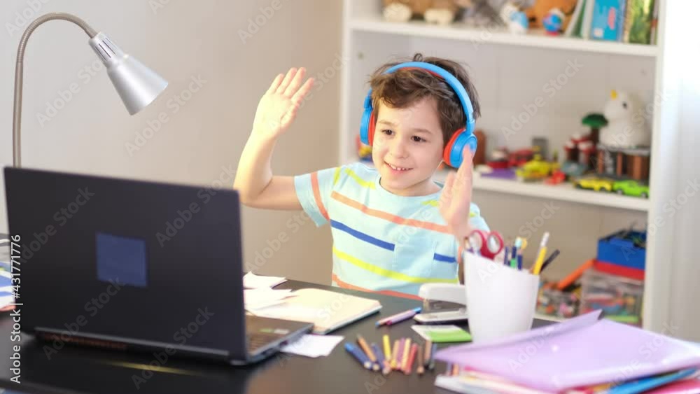 playful boy greets his teacher for an online lesson. online lesson at home, social distance during quarantine, self-isolation, online education concept playful boy greets his teacher for an online lesson. online lesson at home, social distance during quarantine, self-isolation, online education concept