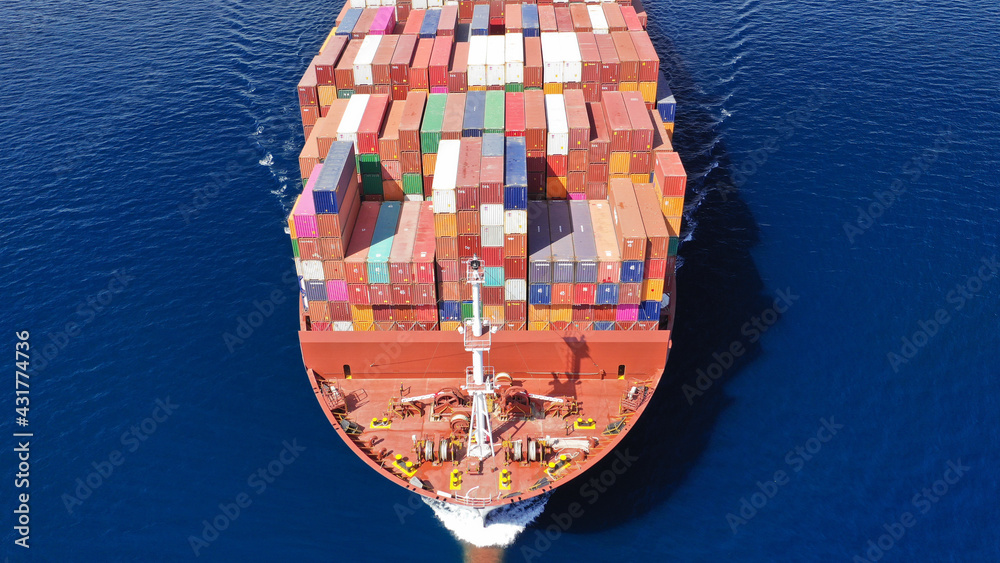 Aerial drone photo of truck size container cargo vessel cruising in deep blue Saronic gulf near commercial port of Piraeus, Attica, Greece