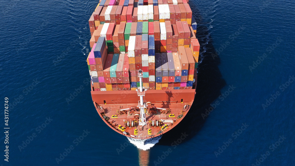 Aerial drone photo of truck size container cargo vessel cruising in deep blue Saronic gulf near commercial port of Piraeus, Attica, Greece