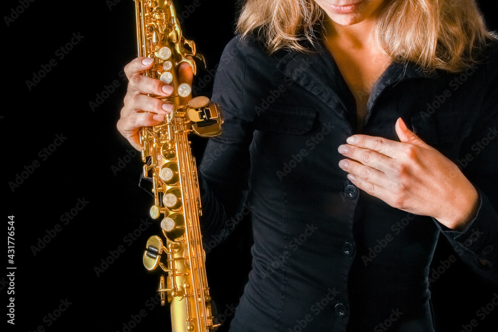 Naklejka premium soprano saxophone in the hands of a girl on a black background