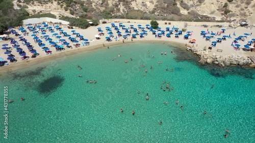 Sand and stone Beach with crystal blue water from drone.