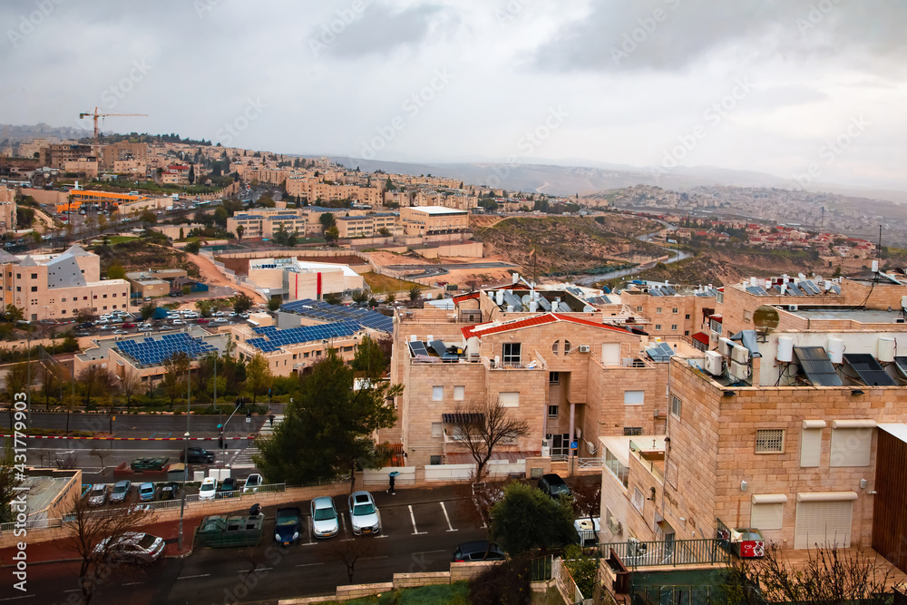 view from the mountain to Jerusalem in cloudy weather. Cars, light stone houses, solar panels on rooftops