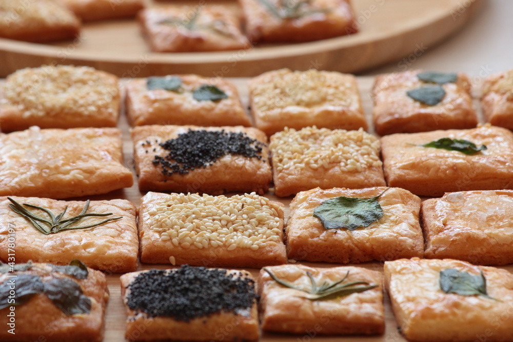 Homemade crackers decorated with herb leaves, sesame seeds, poppy seeds and salt