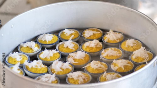 Yellow Toddy Palm Cake (Kanom Tarn) Thai dessert with Tan That has coconut sprinkled on top in the steel Steaming pot. It is a Thai dessert made from Toddy palm