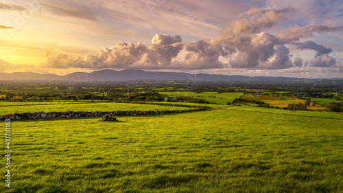 Beautiful sunset with dramatic sky at golden hour over green fields and farms in MacGillycuddys Reeks mountains, Ring of Kerry, Ireland