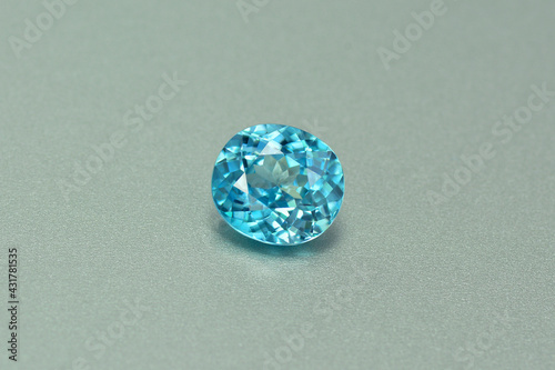 Genuine, natural mined, bright neon blue lagoon color, cushion shaped, heated loose zircon flawless gemstone setting for jewelry making. Light gray gradient background. photo